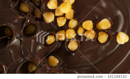 Close-up of Falling Whole Hazelnuts into Melted Chocolate 101109183