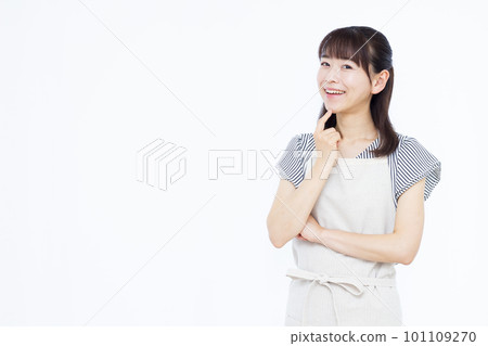 一位三十多歲的家庭主婦圍著圍裙,雙手抱胸微笑思考 一位三十多歲的家庭主婦圍著圍裙,雙手抱胸微笑思考 101109270