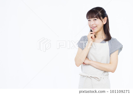 一位三十多歲的家庭主婦圍著圍裙，雙手抱胸微笑思考 101109271