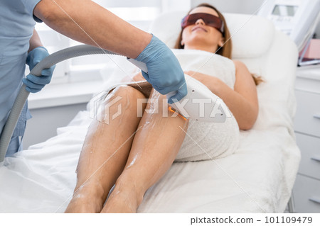 Laser hair removal procedure in a cosmetology beauty salon. Woman cosmetologist removes body hair. 101109479