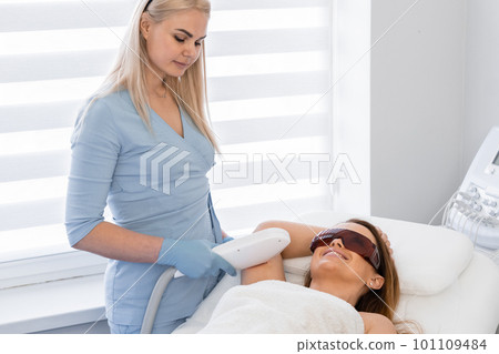 Laser hair removal procedure in a cosmetology beauty salon. Woman cosmetologist removes body hair. 101109484