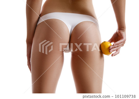 Perfect body of girl in white underwear touching her hip with lemon, isolated on white. Plastic surgery and aesthetic cosmetology concept. Close-up. 101109738