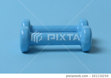 Dumbbells made of blue plastic on blue background Dumbbells made of blue plastic on blue background 101110250