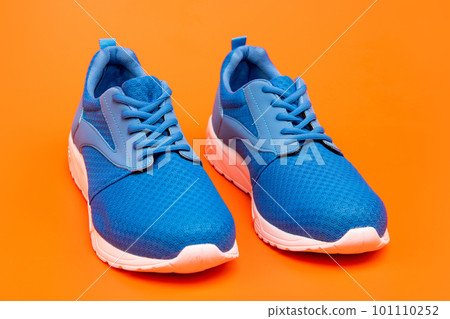 sporty blue sneakers. shoes on orange background. shoe store. shopping concept. sporty blue sneakers. shoes on orange background. shoe store. shopping concept. 101110252