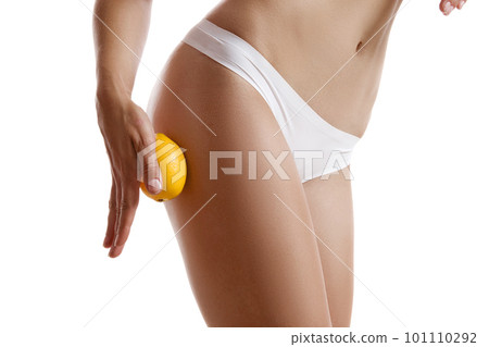 Perfect body of girl in white underwear touching her hip with lemon, isolated on white. Plastic surgery and aesthetic cosmetology concept. Close-up. Perfect body of girl in white underwear touching her hip with lemon, isolated on white. Plastic surgery and aesthetic cosmetology concept. Close-up. 101110292