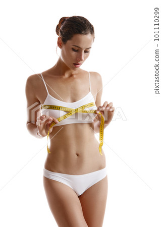 Perfect body of girl in white underwear measuring herself, posing isolated on white. Plastic surgery and aesthetic cosmetology concept. Close-up. Perfect body of girl in white underwear measuring herself, posing isolated on white. Plastic surgery and aesthetic cosmetology concept. Close-up. 101110299