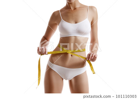 Perfect body of girl in white underwear measuring herself, posing isolated on white. Plastic surgery and aesthetic cosmetology concept. Close-up. Perfect body of girl in white underwear measuring herself, posing isolated on white. Plastic surgery and aesthetic cosmetology concept. Close-up. 101110303
