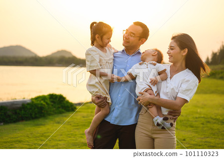 Happy family enjoying in park together on weekend with sunset view 101110323