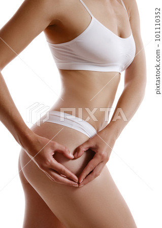 Perfect, slim, toned, young body of a girl in white underwear posing isolated on white. Plastic surgery and aesthetic cosmetology concept. Close-up. Perfect, slim, toned, young body of a girl in white underwear posing isolated on white. Plastic surgery and aesthetic cosmetology concept. Close-up. 101110352