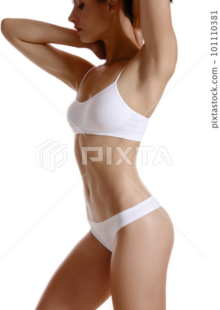 Perfect, slim, toned, young body of a girl in white underwear posing isolated on white. Plastic surgery and aesthetic cosmetology concept. Close-up. 101110381