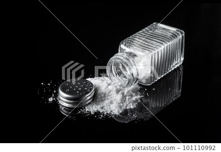 Heap of salt from a salt shaker on black background. The concept of excessive salt intake that can be the cause of diabetes or other diseases 101110992