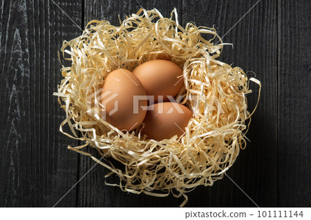 Brown eggs in the nest on the farm. Decorating a nest made of wood sawdust. 101111144