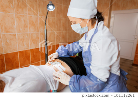 Professional nurse bandages the injured back of a young girl in the surgical department. Professional nurse bandages the injured back of a young girl in the surgical department. 101112261