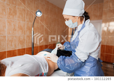 Doctor in a protective mask in medical uniform bandages a bandage to a patient in a hospital ward. Nurse caring for a sick patient after a back injury 101112265