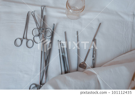 Surgical instruments made of steel including scalpels, forceps and tweezers, located on a white table. Medical equipment. Close-up Surgical instruments made of steel including scalpels, forceps and tweezers, located on a white table. Medical equipment. Close-up 101112435