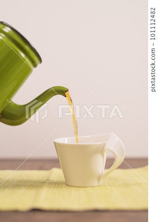 Hojicha being poured from a kettle into a mug 101112482