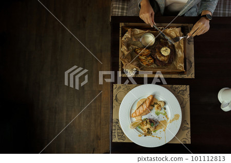 Woman eating meat steak with baked vegetables in a restaurant. Healthy and tasty lunch. Top view of the dining table 101112813