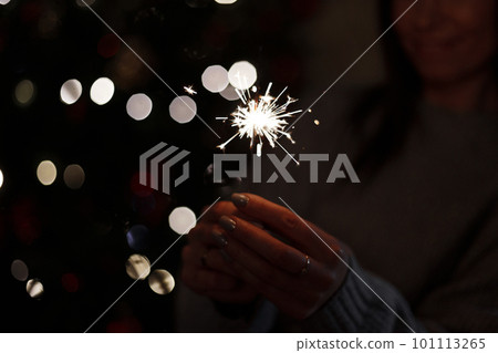 Beautiful bright celebratory sparkler in woman hands on a light background. Close-up. Beautiful bright celebratory sparkler in woman hands on a light background. Close-up. 101113265