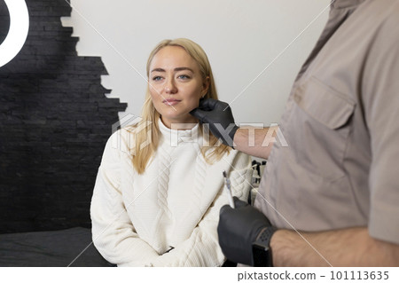 Doctor pulls female facial skin, lifting temple area, preparing to face reshape with filler, injection, surgery. Beauty physician, female patient are in examination room.Aesthetic medicine.Horizontal. 101113635