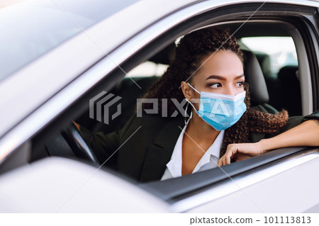 Young woman driving car with protective mask on her face.Transport isolation to stop spread of virus Young woman driving car with protective mask on her face.Transport isolation to stop spread of virus 101113813