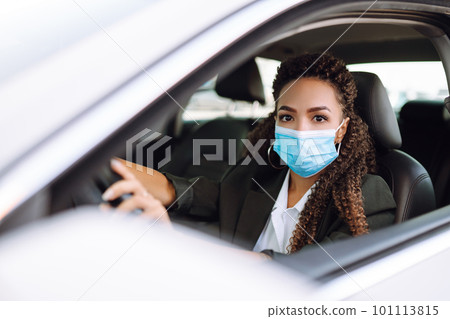 Young woman driving car with protective mask on her face.Transport isolation to stop spread of virus Young woman driving car with protective mask on her face.Transport isolation to stop spread of virus 101113815
