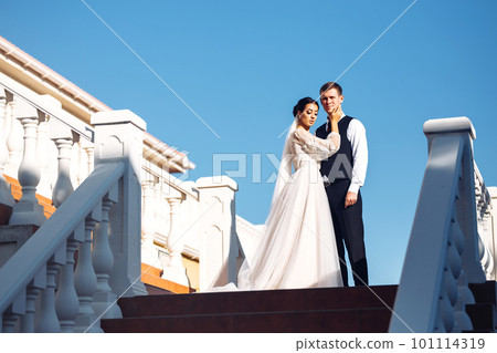 The bride and groom on the steps of the stairs. Elegant stylish young couple enjoy each other on the stairs. The bride and groom on the steps of the stairs. Elegant stylish young couple enjoy each other on the stairs. 101114319