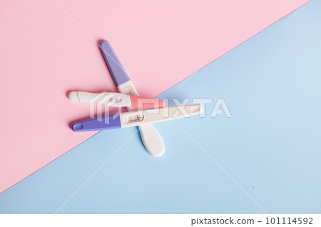Flat lay composition with pregnancy tests stacked on blue and pink pastel background with copy ad space. Women's health, fertility and rapid pregnancy diagnostics concept 101114592