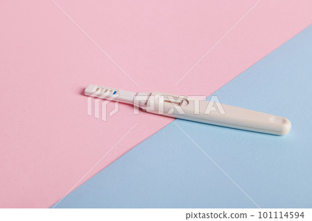 Still life. Pregnancy test with positive result between HCG hormone in female urine, isolated on pink and blue pastel background. Rapid diagnosis of pregnancy. Women's health and fertility concept 101114594