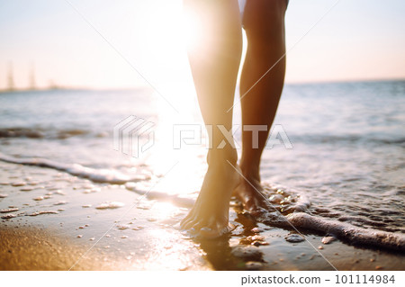 Close- up leg of young woman walking along wave of sea water and sand on the summer beach. Close- up leg of young woman walking along wave of sea water and sand on the summer beach. 101114984