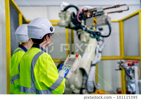 Back of professional technician or engineer use controller to work with factory robotic arm machine Back of professional technician or engineer use controller to work with factory robotic arm machine 101115395