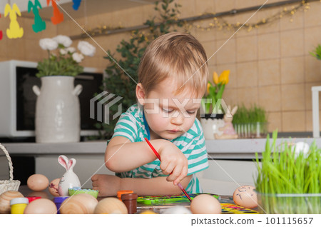 Toddler boy painting Easter egg close-up. Easter traditions and entertainment with children at home 101115657