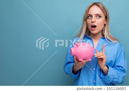 pensive blond girl holding a piggy bank with a stock thinks where to spend money on a blue isolated pensive blond girl holding a piggy bank with a stock thinks where to spend money on a blue isolated 101116003