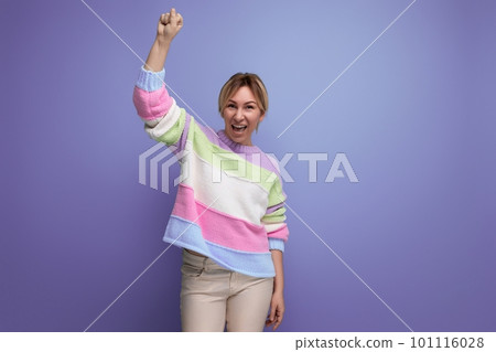 successful charming blond young woman raised her hand into a fist on a purple background 101116028