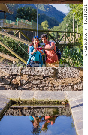 Eco friendly ancient lavoir washhouse. Mixed race mid couple photographing with smartphone. Eco friendly ancient lavoir washhouse. Mixed race mid couple photographing with smartphone. 101116231