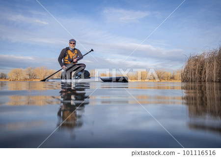 senior paddler and his paddleboard on lake in winter or early spring in Colorado, frog perspective (partially submerged action camera) 101116516