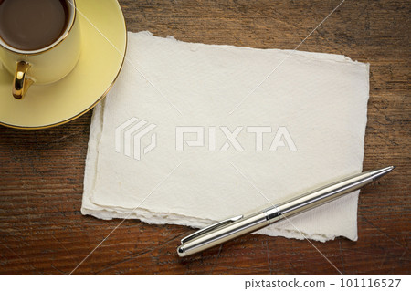 small sheet of blank white Khadi rag paper on rustic wooden table with coffee 101116527