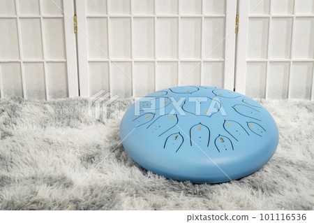 blue steel tongue drum on a fluffy rug 101116536