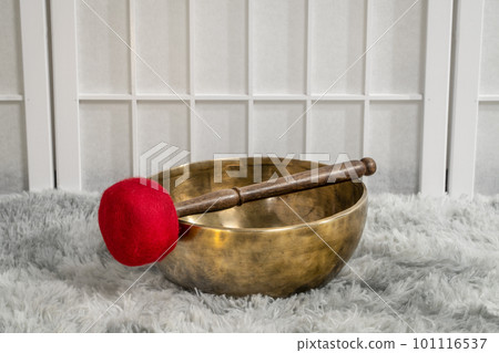 handmade Tibetan singing bowl with a mallet on a fluffy rug, sound therapy for healing, relaxation and meditation 101116537