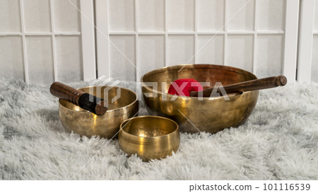 handmade Tibetan singing bowls with mallets on a fluffy rug, sound therapy for healing, relaxation and meditation handmade Tibetan singing bowls with mallets on a fluffy rug, sound therapy for healing, relaxation and meditation 101116539