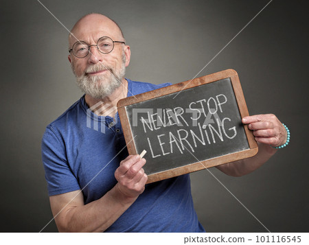 Never stop learning - motivation note on a slate blackboard held by a senior man, teacher, mentor or presenter, education, business and personal development concept communication concept 101116545