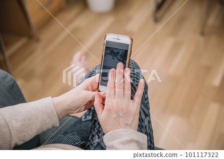 Elderly woman holding and using smartphone, mobile phone. Grandmother hands. Close up view, family connection concept 101117322