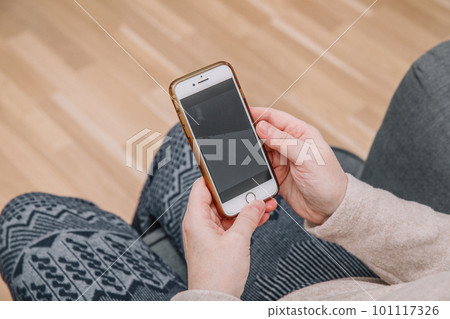 An elderly woman holds and uses a smartphone in her hand, a smartphone. Grandmother. Closeup, the concept of family connections 101117326