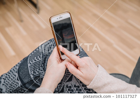An elderly woman holds and uses a smartphone in her hand, a smartphone. Grandmother. Closeup, the concept of family connections 101117327