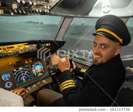 Caucasian bearded man smiling while driving a flight simulator. Pilot in the cockpit showing thumbs up. Caucasian bearded man smiling while driving a flight simulator. Pilot in the cockpit showing thumbs up. 101117730