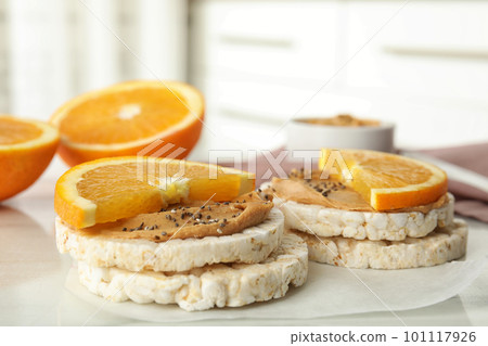 Puffed rice cakes with peanut butter and orange on white table, closeup Puffed rice cakes with peanut butter and orange on white table, closeup 101117926