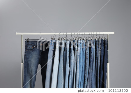 Rack with different jeans on grey background 101118300