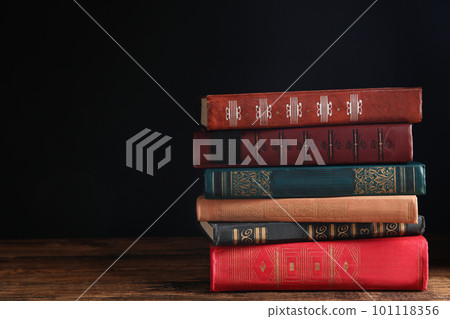 Collection of different books on wooden table against dark background. Space for text 101118356