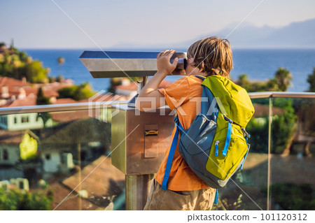 Boy tourist looks through binoculars in Old town Kaleici in Antalya. Turkiye. Panoramic view of Antalya Old Town port, Taurus mountains and Mediterrranean Sea, Turkey. Traveling with kids concept Boy tourist looks through binoculars in Old town Kaleici in Antalya. Turkiye. Panoramic view of Antalya Old Town port, Taurus mountains and Mediterrranean Sea, Turkey. Traveling with kids concept 101120312