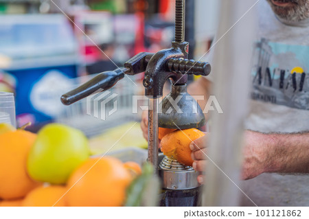 Freshly squeezed juice, street food. Man's hands making orange juice Freshly squeezed juice, street food. Man's hands making orange juice 101121862
