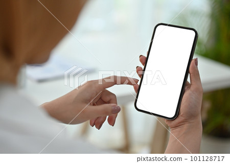 View over shoulder of woman hand holding smart phone. White empty screen for app or web site design View over shoulder of woman hand holding smart phone. White empty screen for app or web site design 101128717